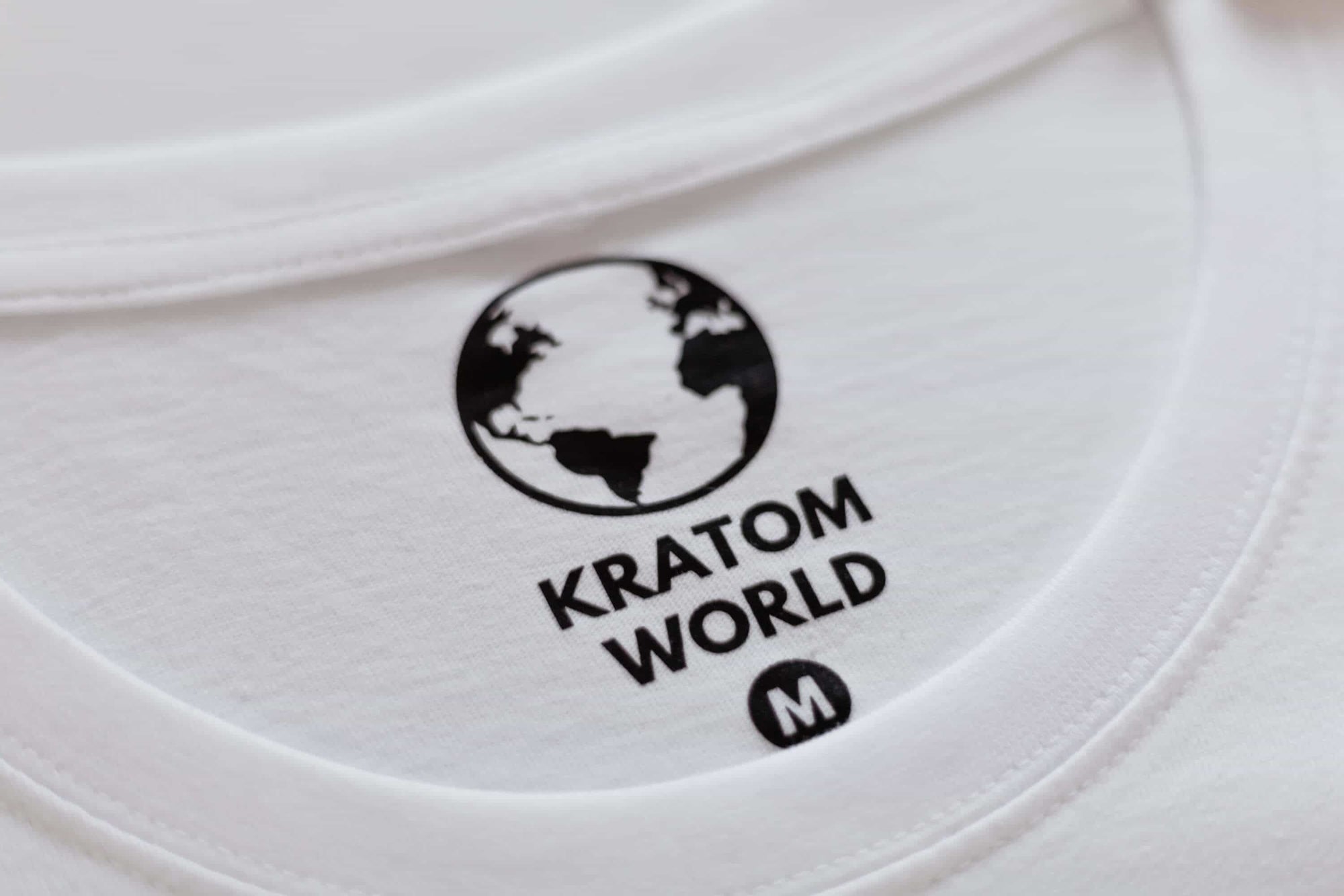 Detaliu al tricoului alb Kratom World cu etichetă de marcă